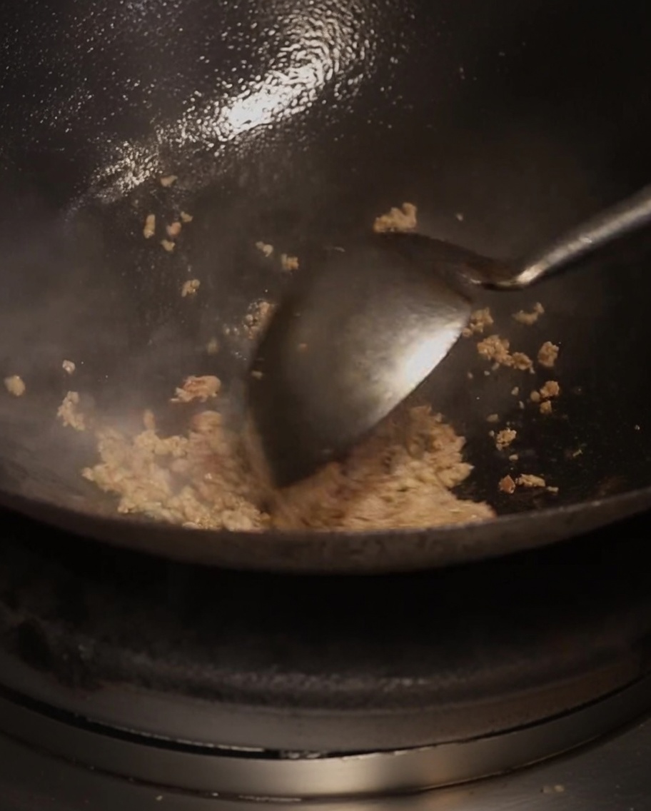 油をひいた熱い中華鍋で炒められるひき肉と調味料