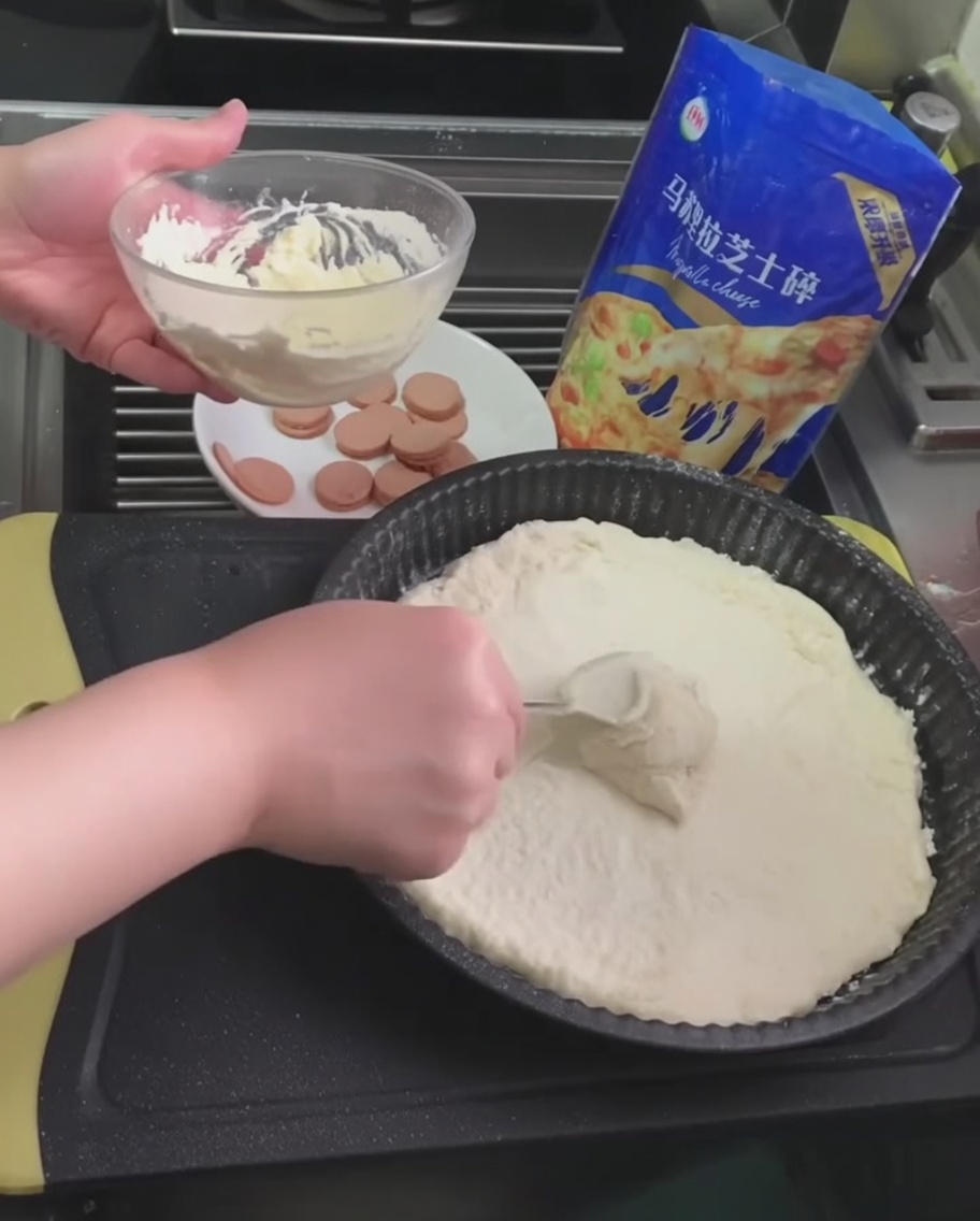 スプーンを使ってピザ生地に白いトリュフソースを広げている様子。
