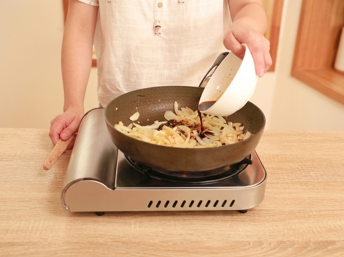 フライパンの具材に合わせ調味料を注ぎ込んでいる様子。