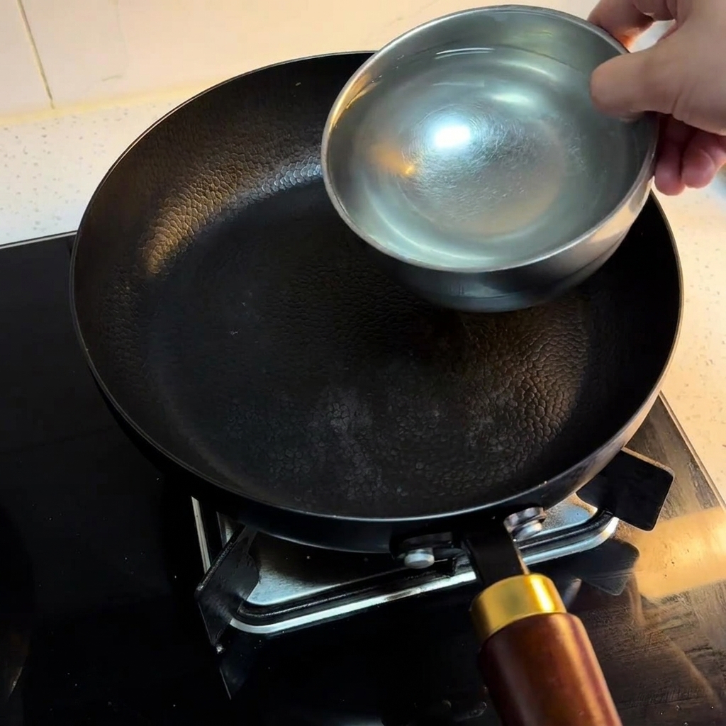 コンロに置かれた黒い鍋に3杯の水が注がれている様子。