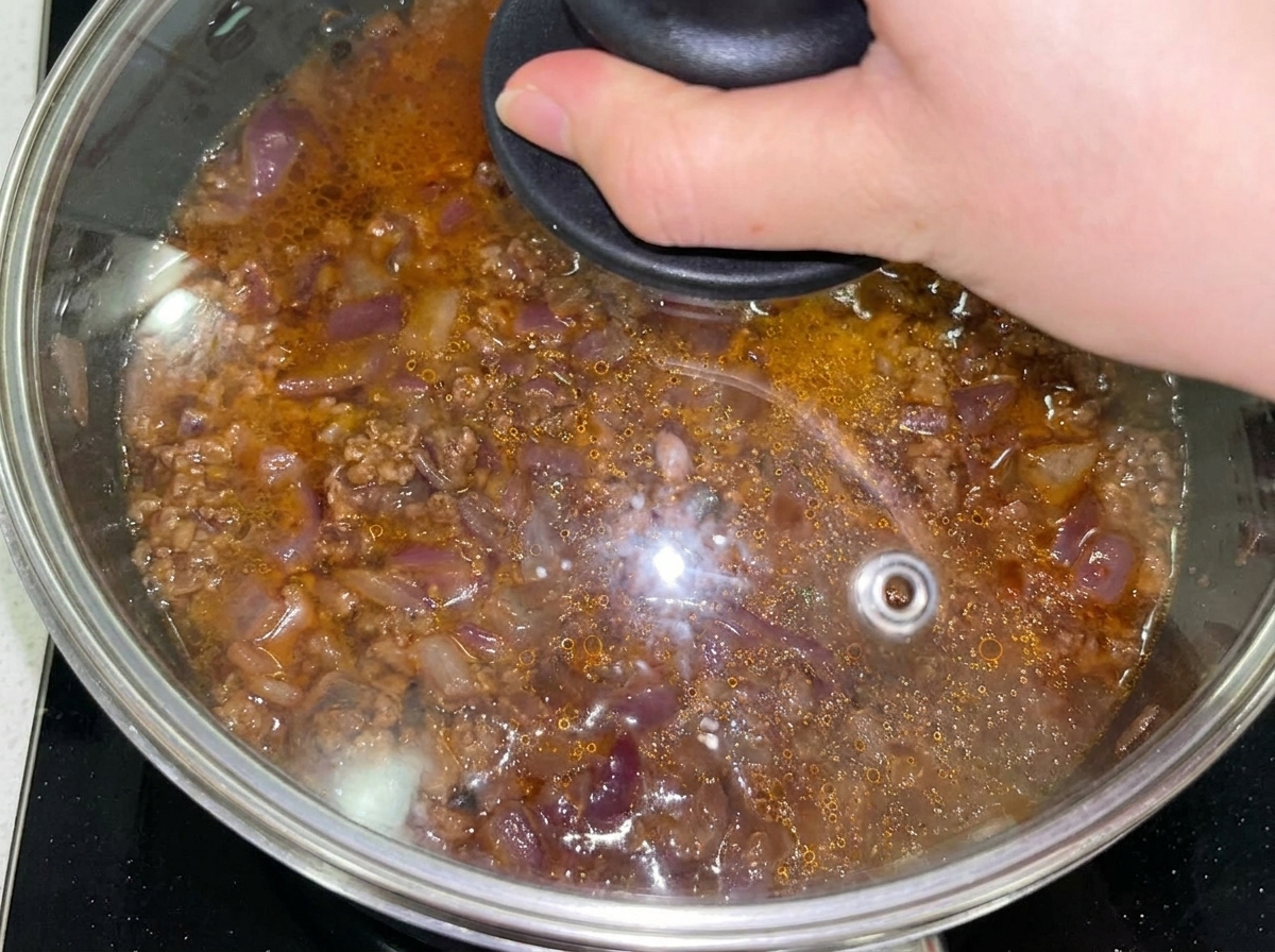フライパンにひたひたの水を加え、蓋をして煮込んでいる様子。