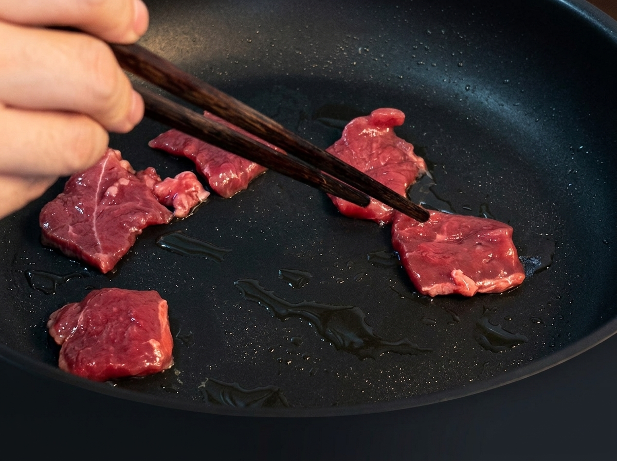 熱したフライパンで牛肉を炒め、色が変わっていく様子