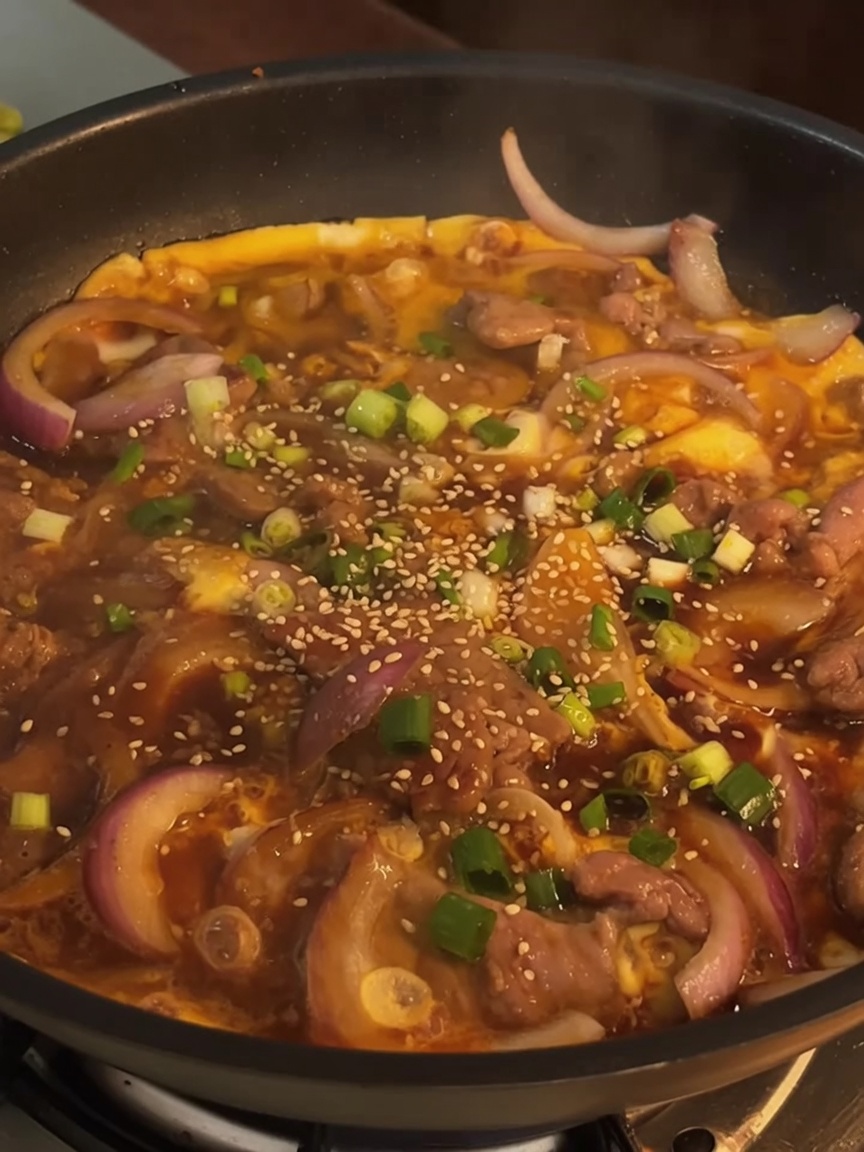 完成した牛丼風の卵とじに青ネギとゴマを散らしている様子