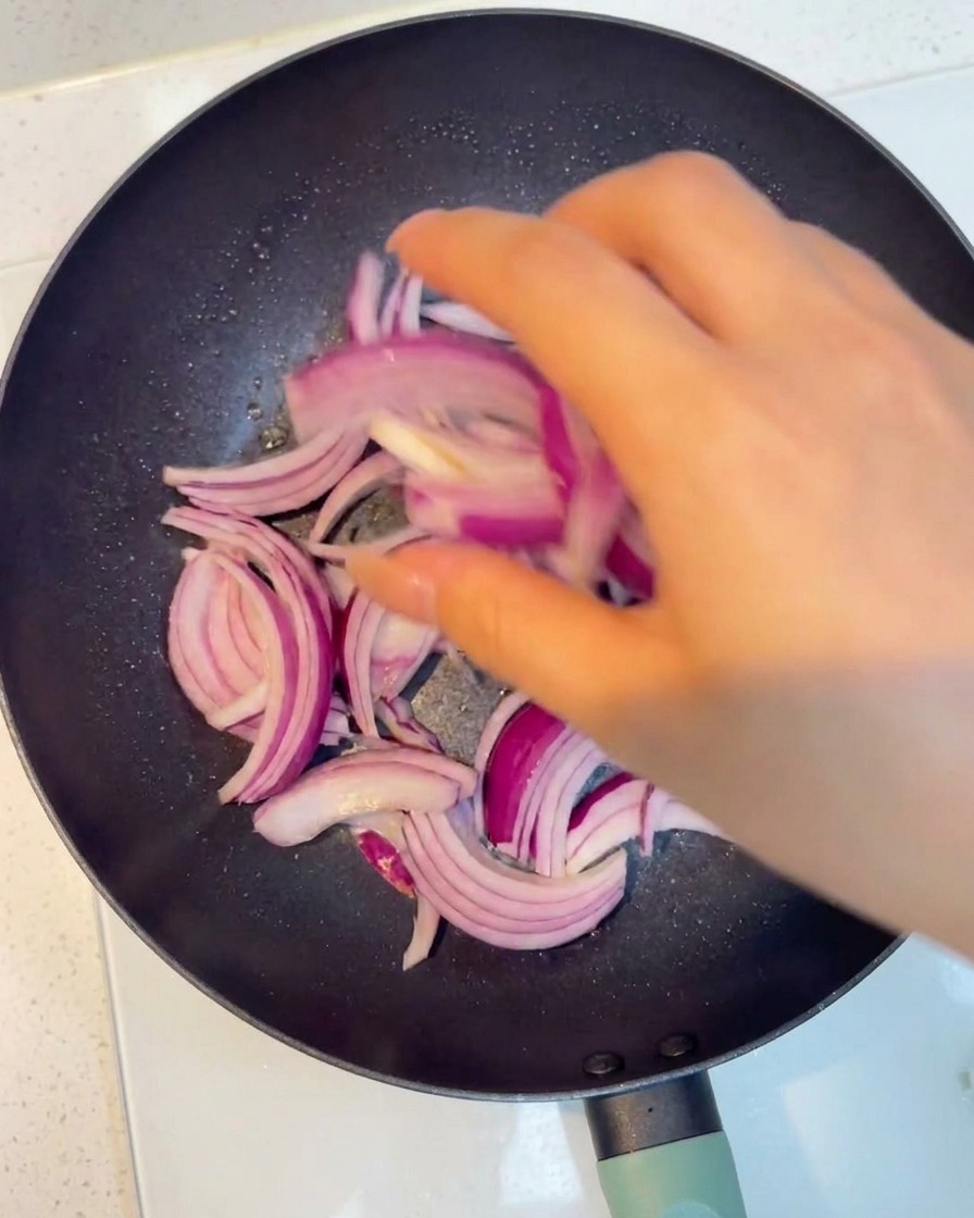 スライスした赤玉ねぎが透き通るまで炒められている様子。