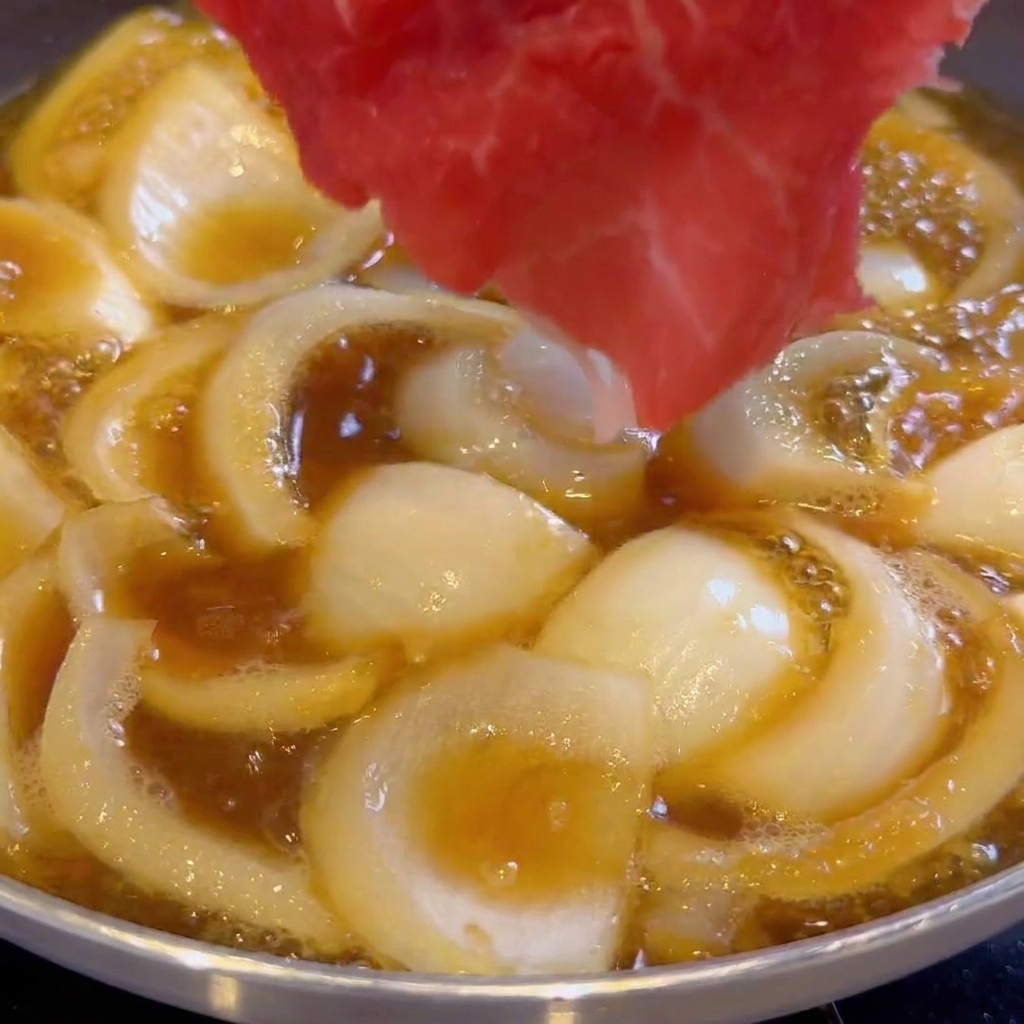 煮汁の中に牛肉を広げながら入れている様子。