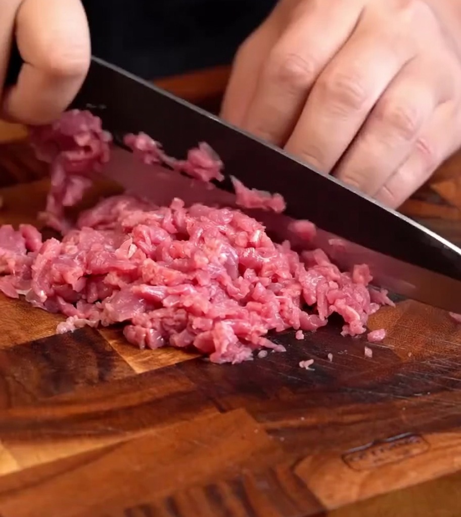 まな板の上で細かく刻まれた、粘り気のある新鮮な牛肉。