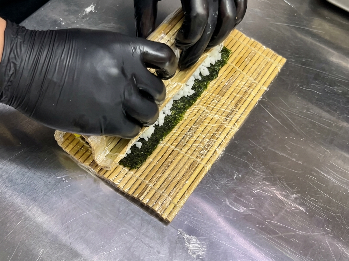 巻きすを使って寿司を円柱状に整えている様子。
