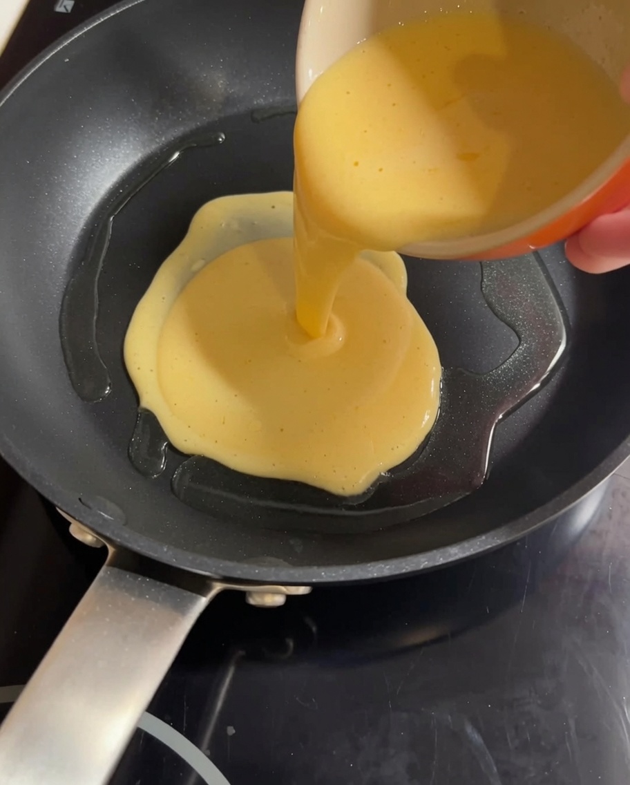 熱したフライパンに、卵と牛乳を合わせた液を流し入れている様子。