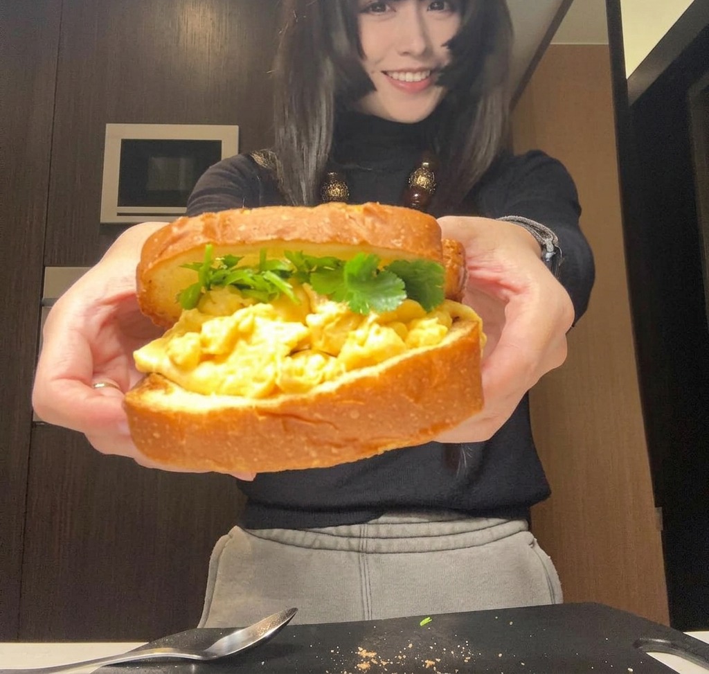 両手でしっかりと持たれた、完成したボリューム満点のサンドイッチ。これからラップで包むところ。