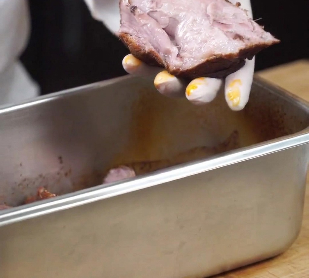 焼き上がった柔らかい豚肉を、手でほぐしている様子。