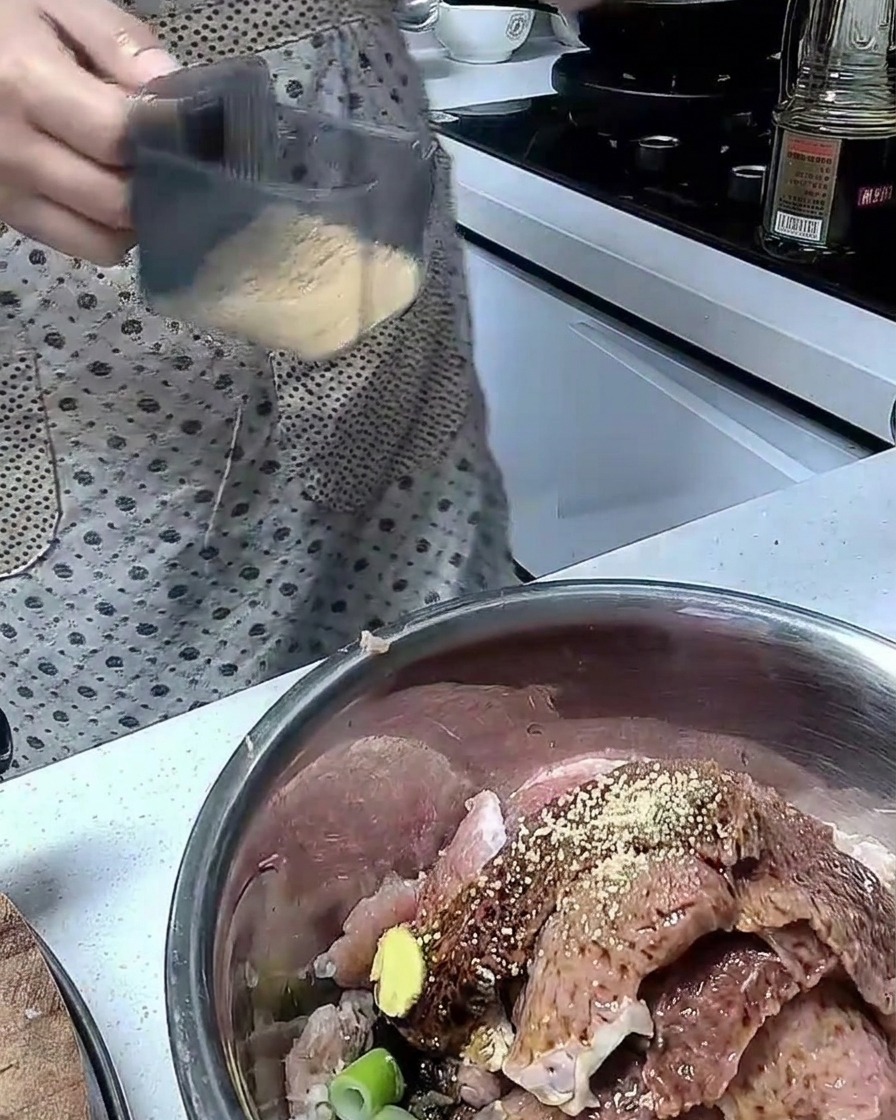 ステンレス製のボウルの中で、調味料と豚肉を混ぜ合わせている様子。
