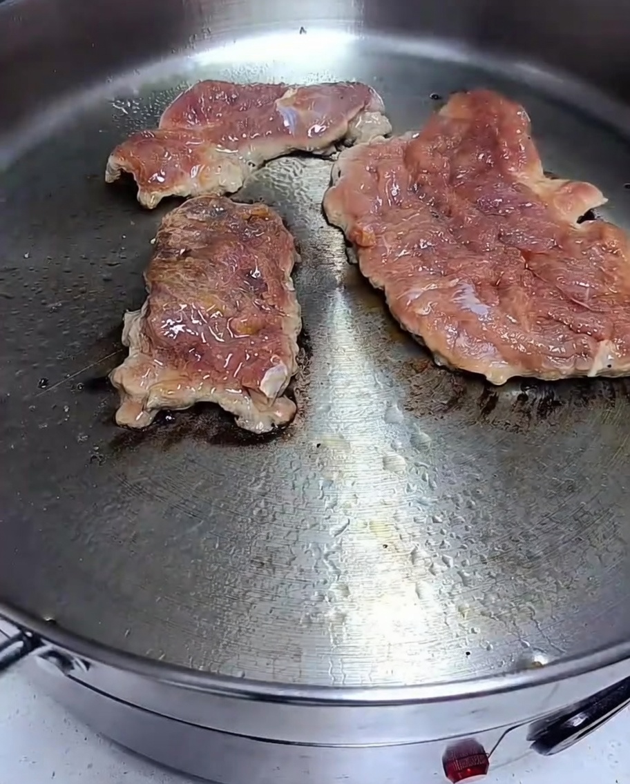 フライパンで豚肉を焼いており、表面に焼き色がついている様子。