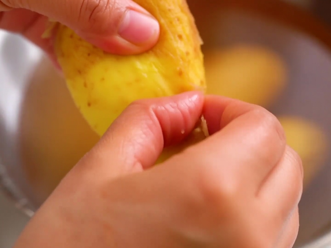 解凍したポテトの皮を指でむいている様子。