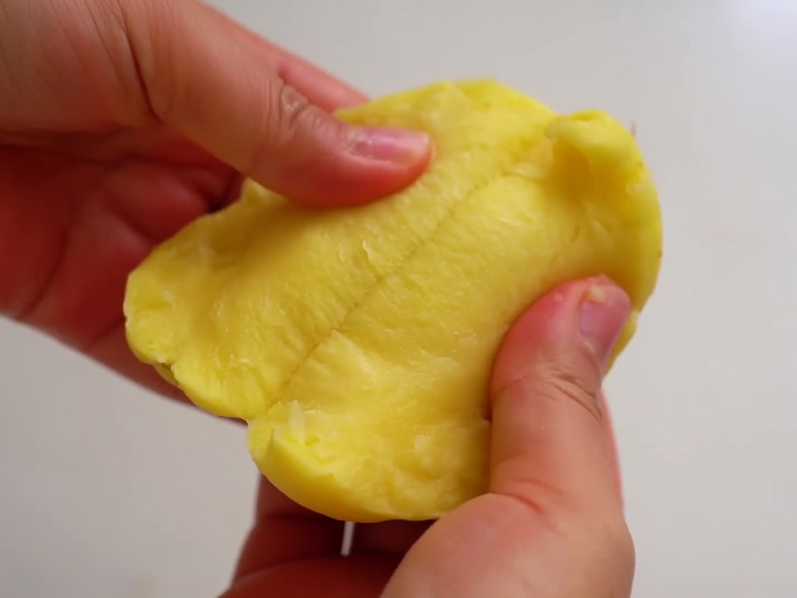 皮をむいたポテトを手で二つに割っている様子。