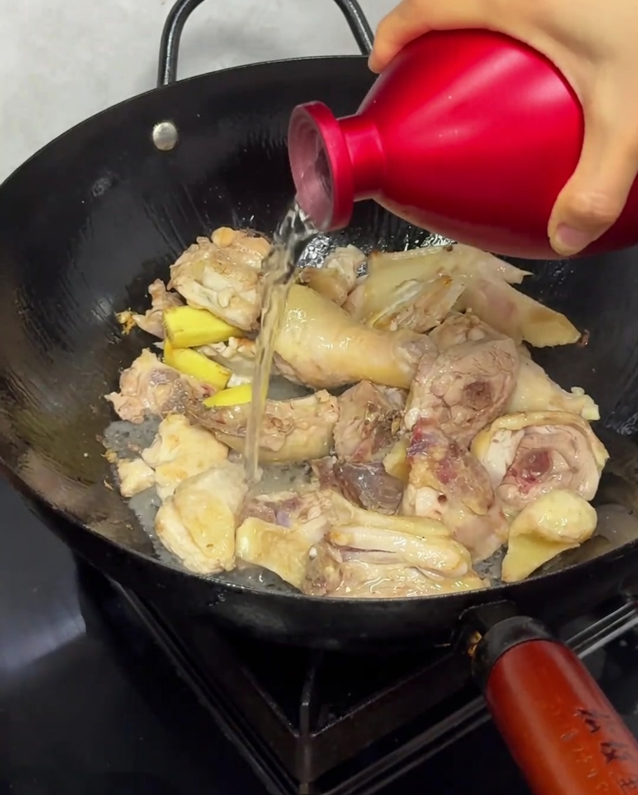 炒めている鶏肉に酒を注いでいる様子。