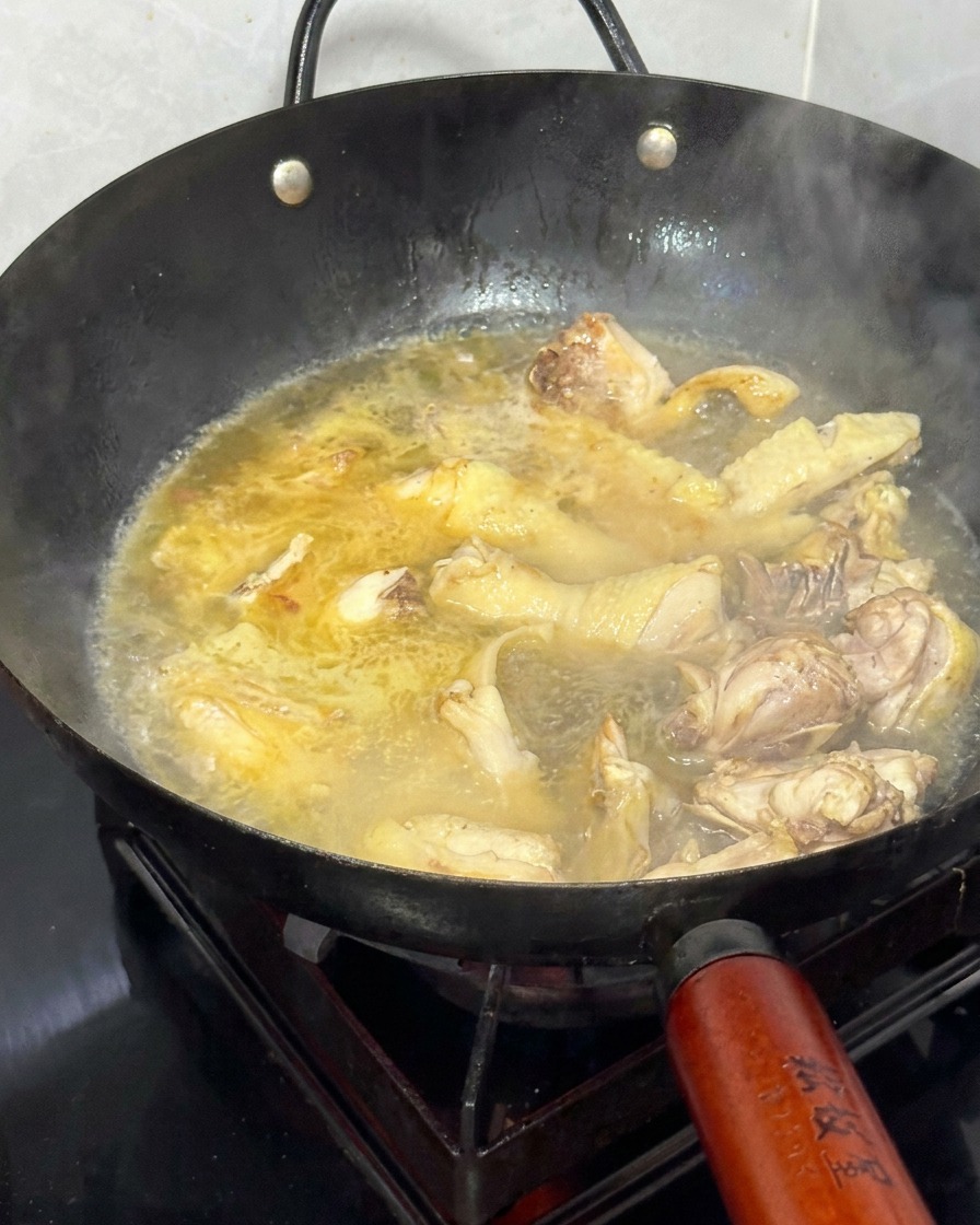 炒めた鶏肉とショウガの鍋に熱湯を注いでいる様子。