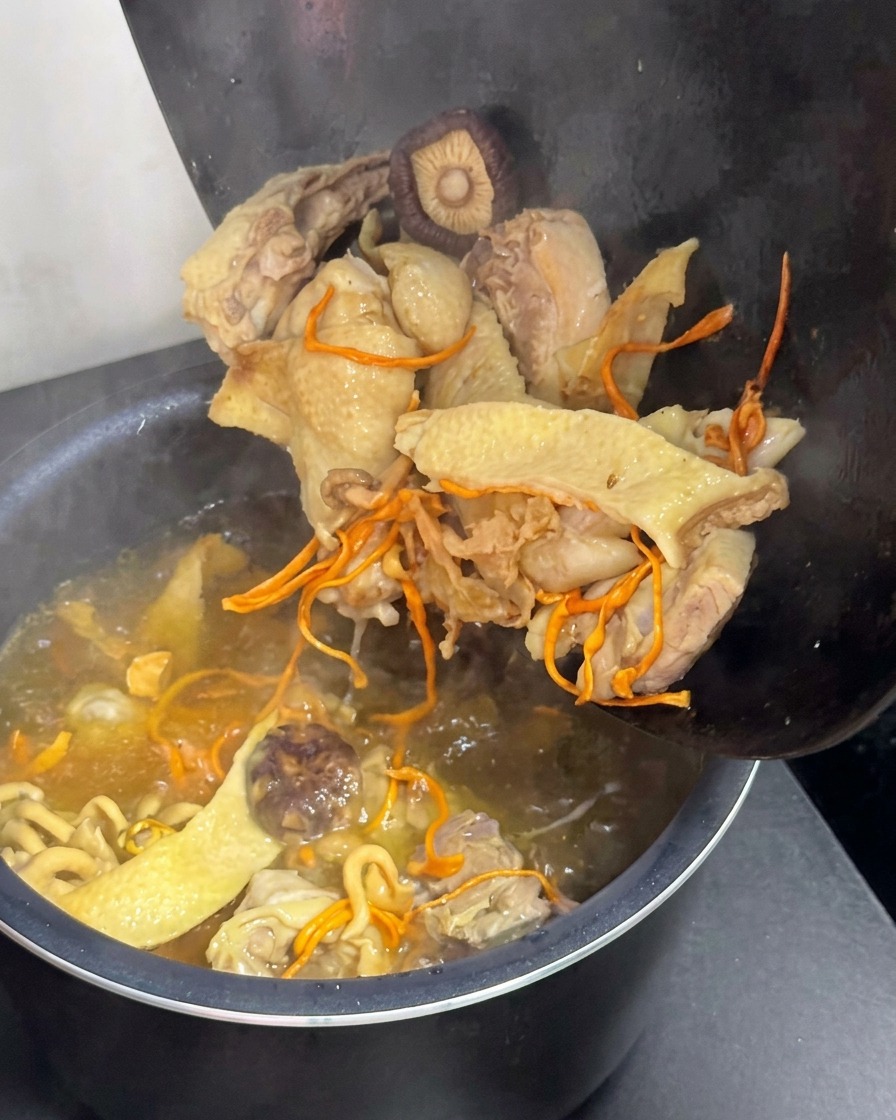 鶏肉と椎茸を電気炊飯器に入れて煮込んでいる様子。