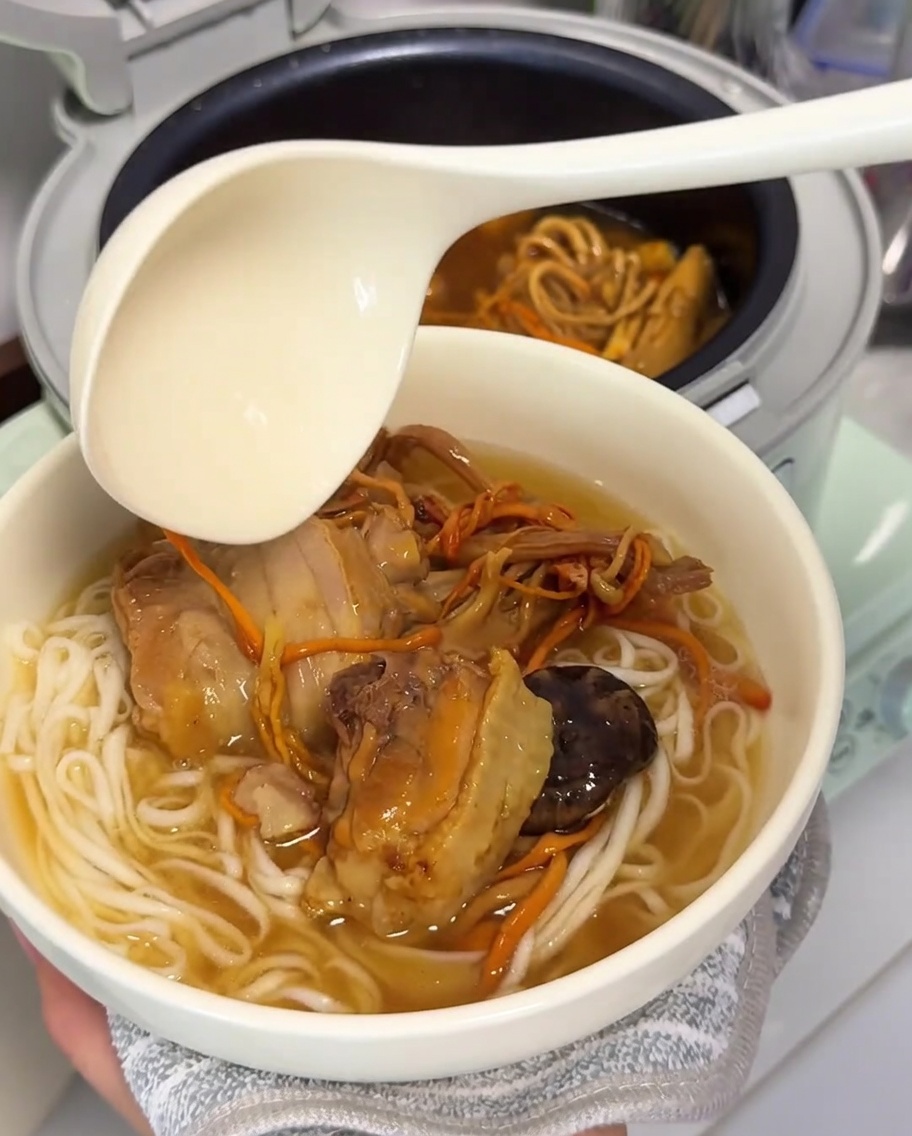 茹で上がった麺に熱々の鶏肉スープを注ぎ入れている様子。