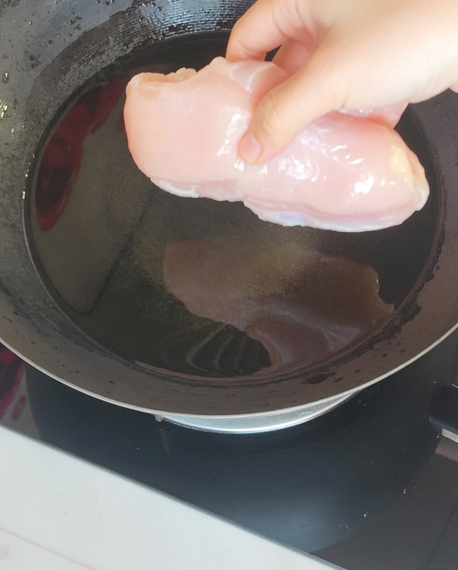 中華鍋で生姜と長ねぎと共に茹でられる鶏むね肉