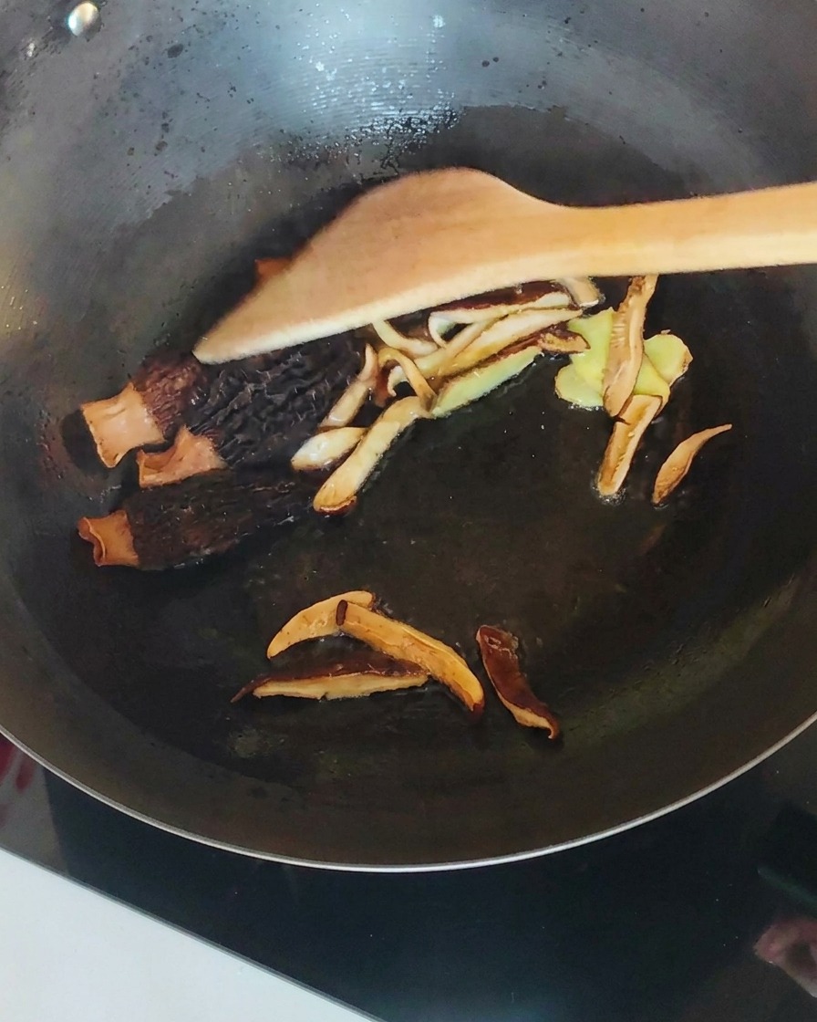 炒めたきのこの鍋に裂いた鶏肉を混ぜ合わせる様子