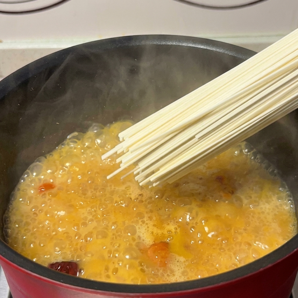 黄金色の鶏スープに麺を投入する様子。