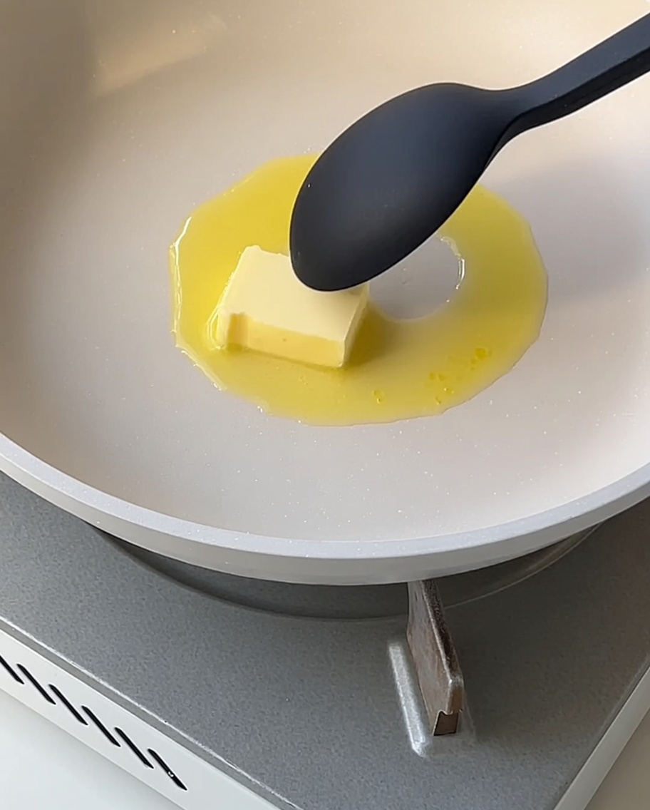 鍋の中でとろみがついたなめらかなホワイトソースをスプーンで混ぜている様子