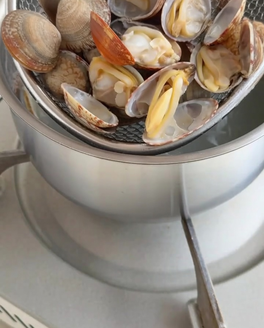 茹で上がったあさりの身を殻から外している様子。