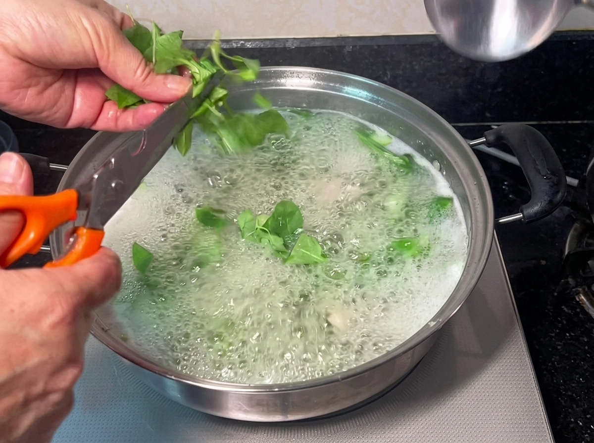 仕上げに塩を加えて味を調えている、煮立っているスープ鍋。