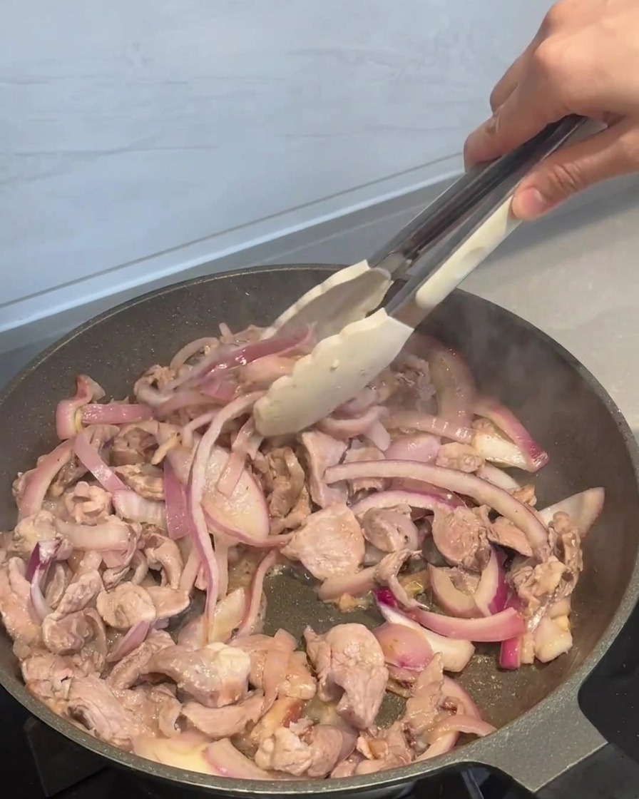 炒めた肉にタレを回し入れる様子。