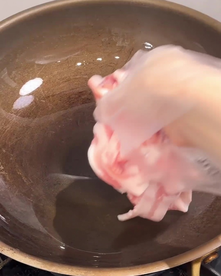 熱したフライパンに薄切りの豚バラ肉を入れている様子。