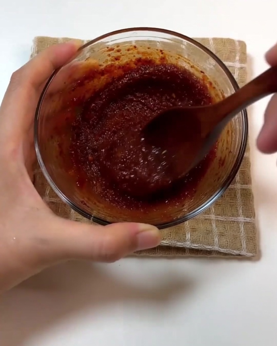 焼いた豚肉にソースと丸ごとニンニクを加える様子。