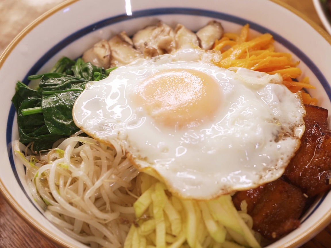 丼の中央にのせられた目玉焼きと、その上からかけられる真っ赤な特製ソース