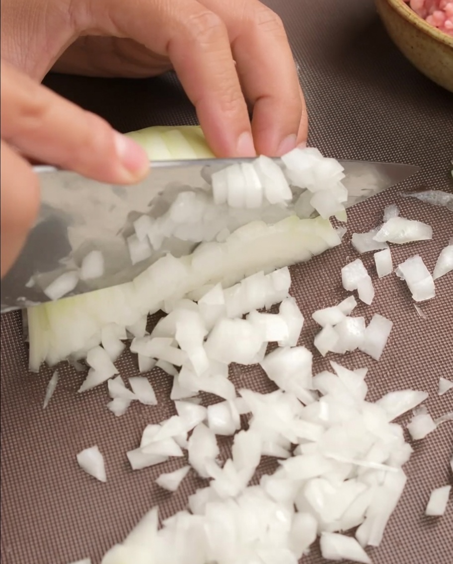 みじん切りにした玉ねぎを肉だねに加える様子