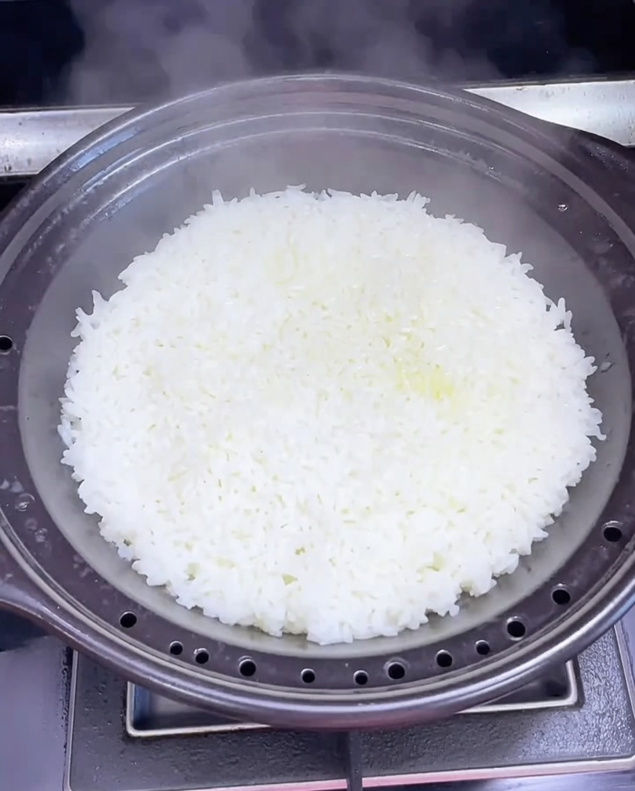 石鍋のご飯から湯気が上がり、箸で穴を開けている様子。