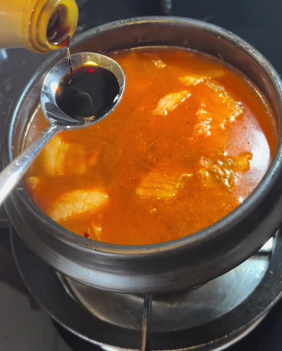 沸騰したスープにスプーン一杯の醤油を加えている様子。