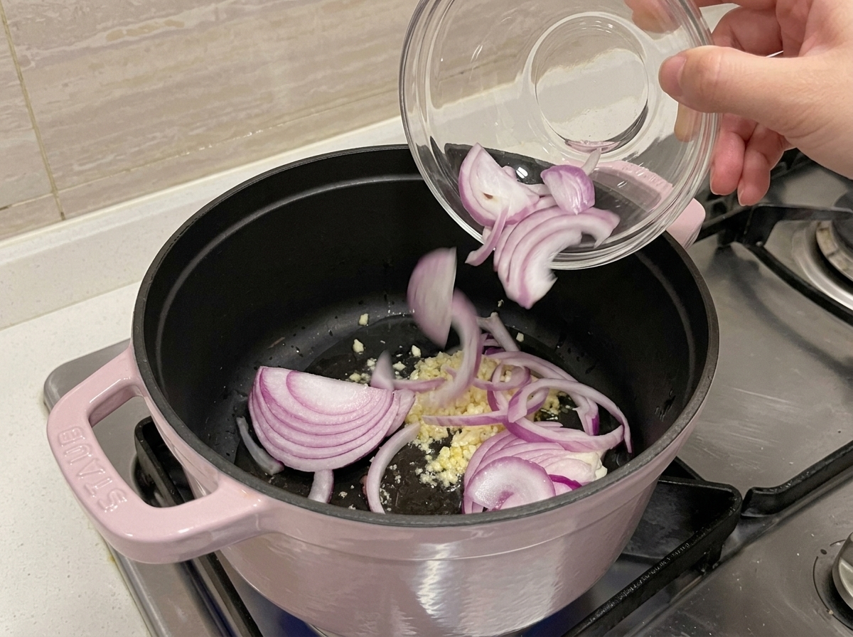 鍋で油とにんにく、赤玉ねぎを炒める様子