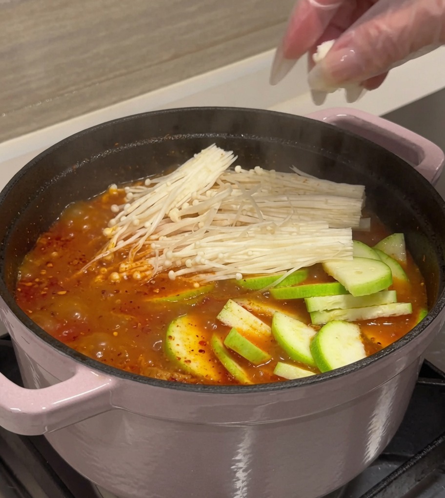 沸騰するキムチスープに具材を加える様子