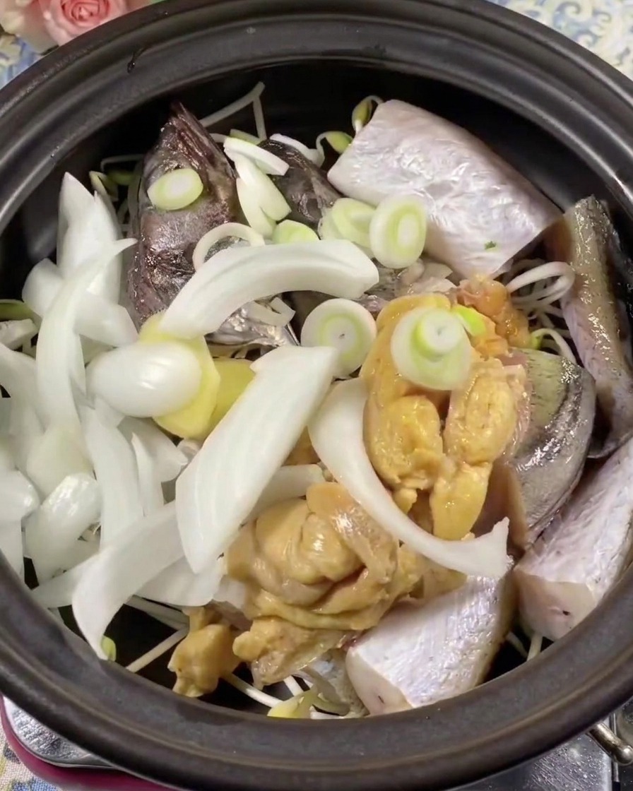 魚と玉ねぎの上に青唐辛子と赤唐辛子のスライスを乗せている様子。