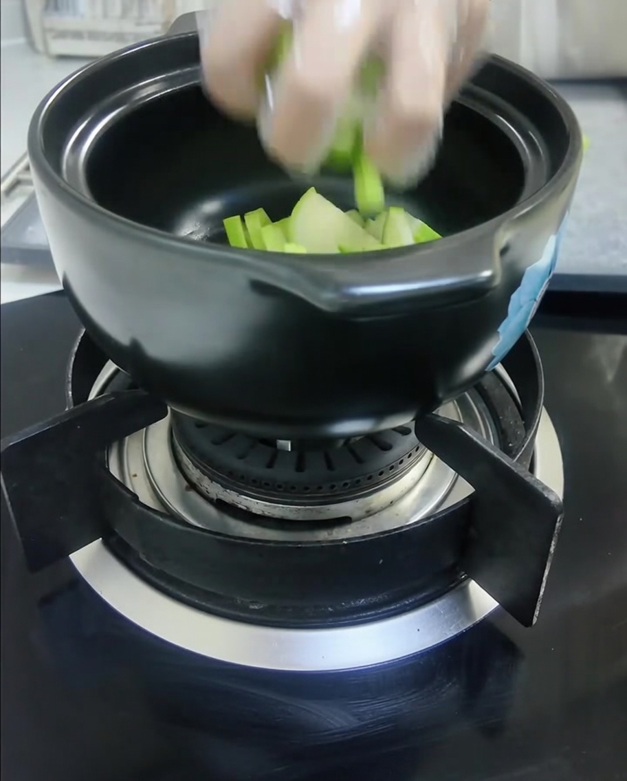 カットしたカボチャと玉ねぎを黒い土鍋に入れた様子。