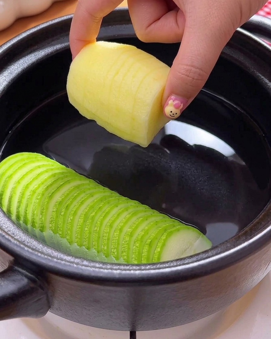 煮立っているチゲに、スライスした豆腐、粉唐辛子、生の唐辛子を加えている様子。
