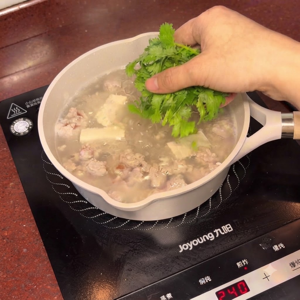 湯気の立つ梅干しと豆腐のスープに、新鮮な刻んだパクチーが振りかけられている様子。