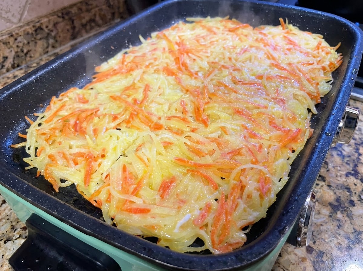 大きなポテトパンケーキをフライパンの中でフライ返しを使って切り分けている様子。