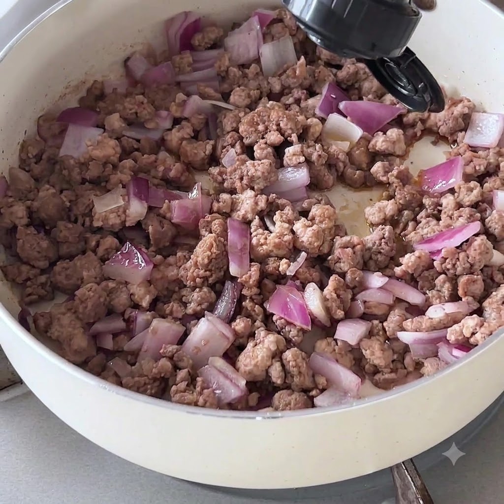 フライパンの牛ひき肉と玉ねぎにボトルからダークソイソースを注いでいる様子。