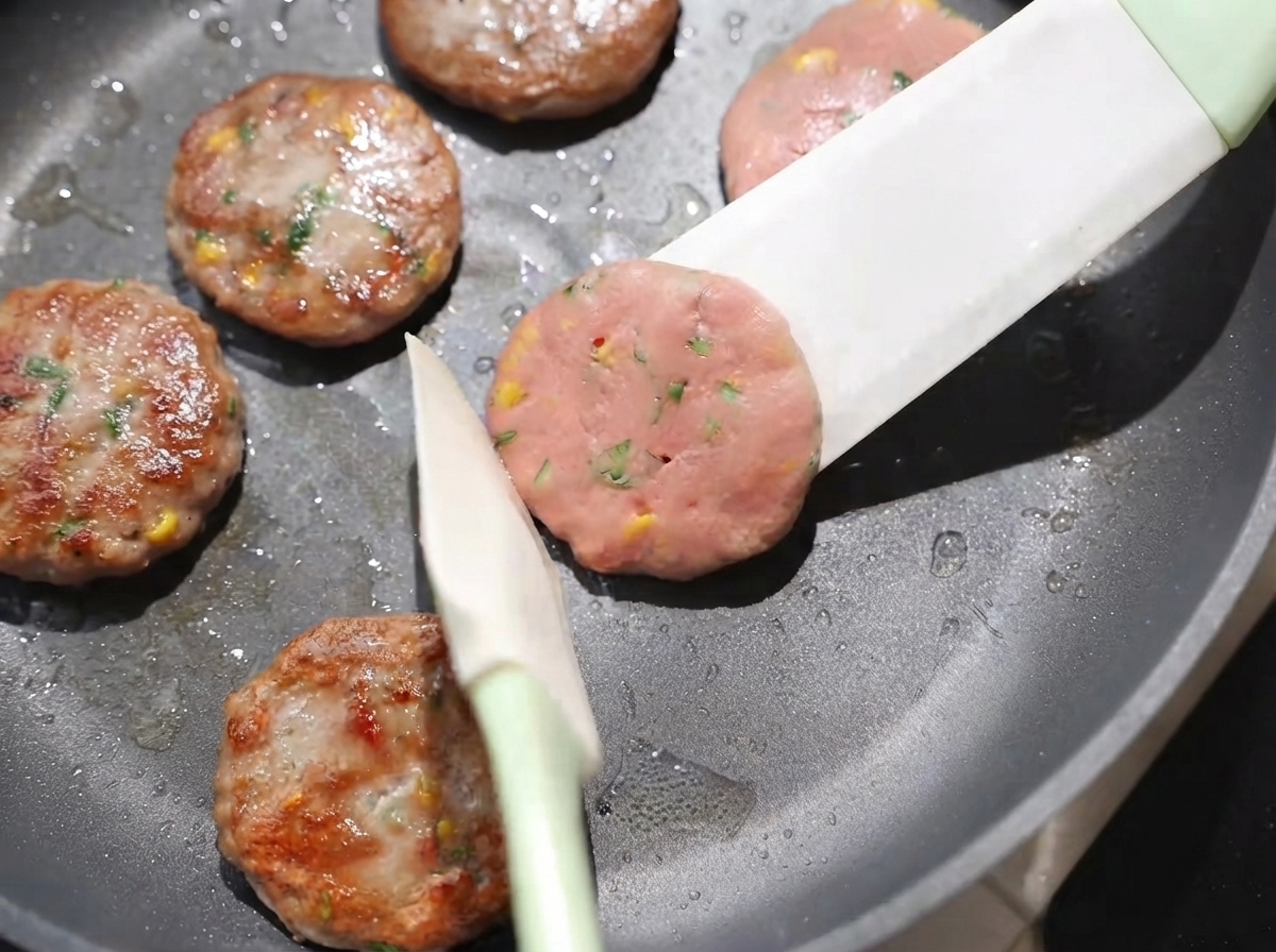 フライ返しでパティを裏返し、弱火でキツネ色に焼いている様子