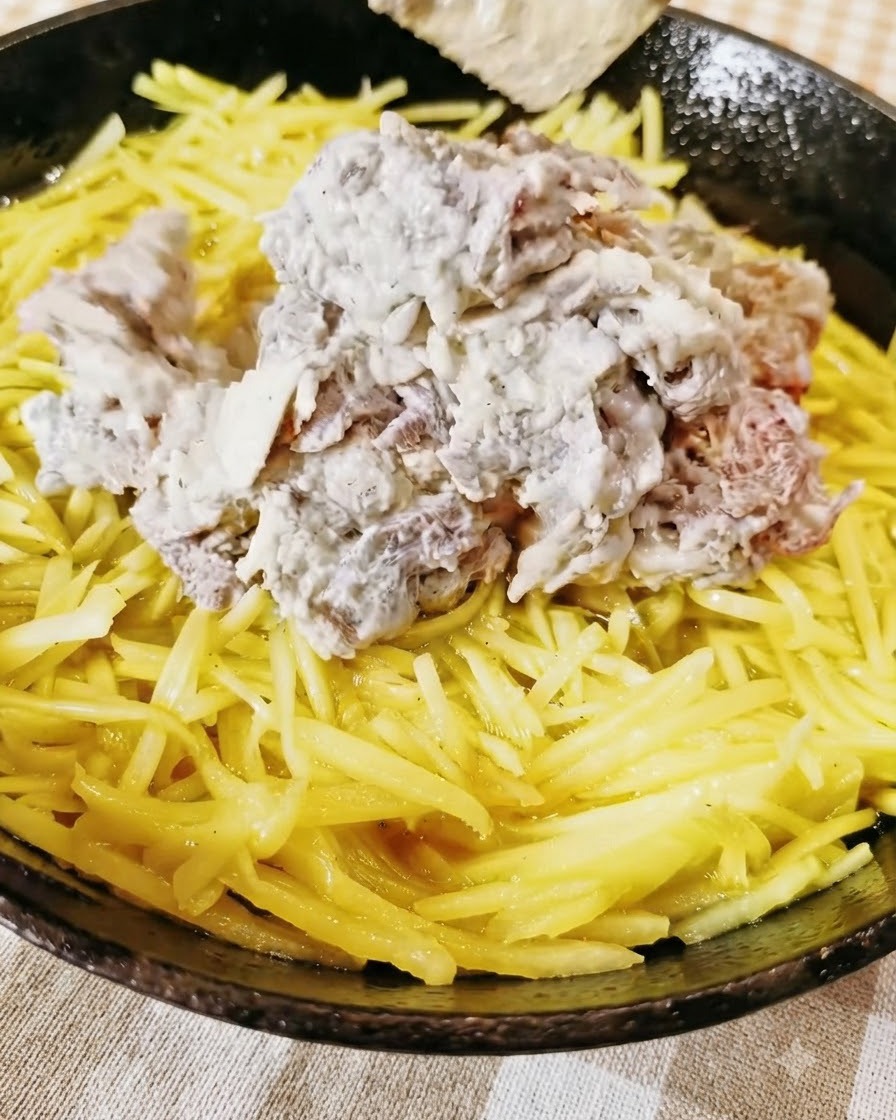 スキレットの中の黄色い千切りじゃがいもの層の上に、味付けしたひき肉が山盛りにされている様子