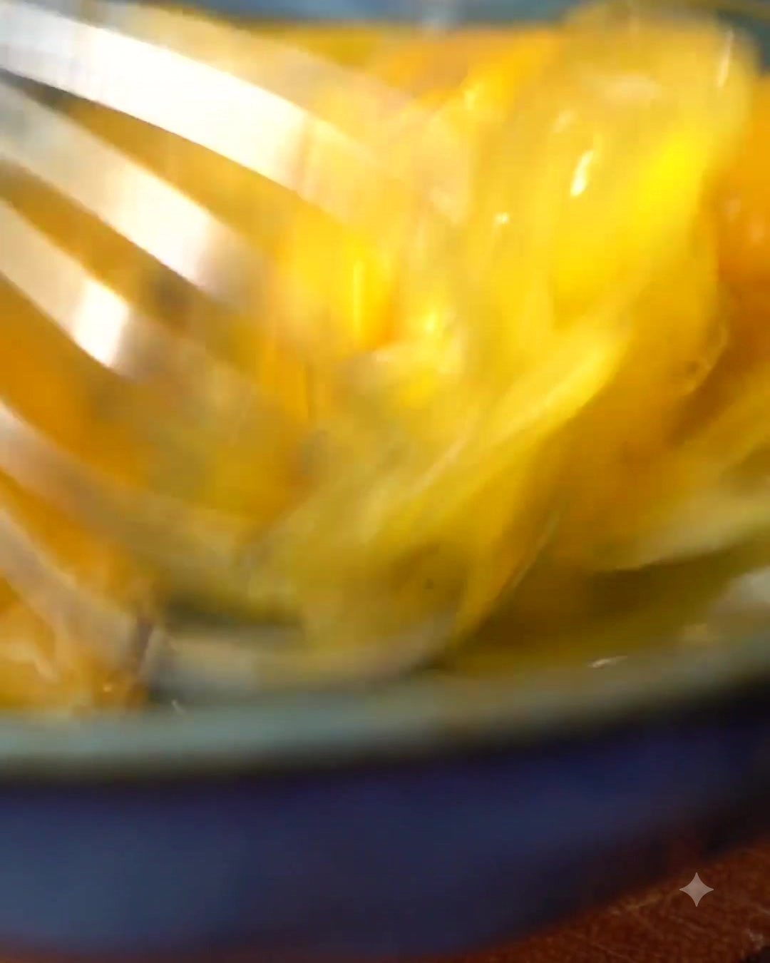 調味料を入れたボウルの中で、泡立て器を使って卵を溶いている様子。