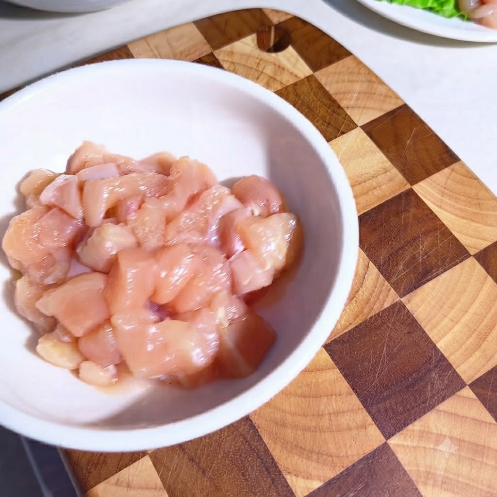 ボウルに入った鶏肉に調味料とオリーブオイルをまぶしている様子。
