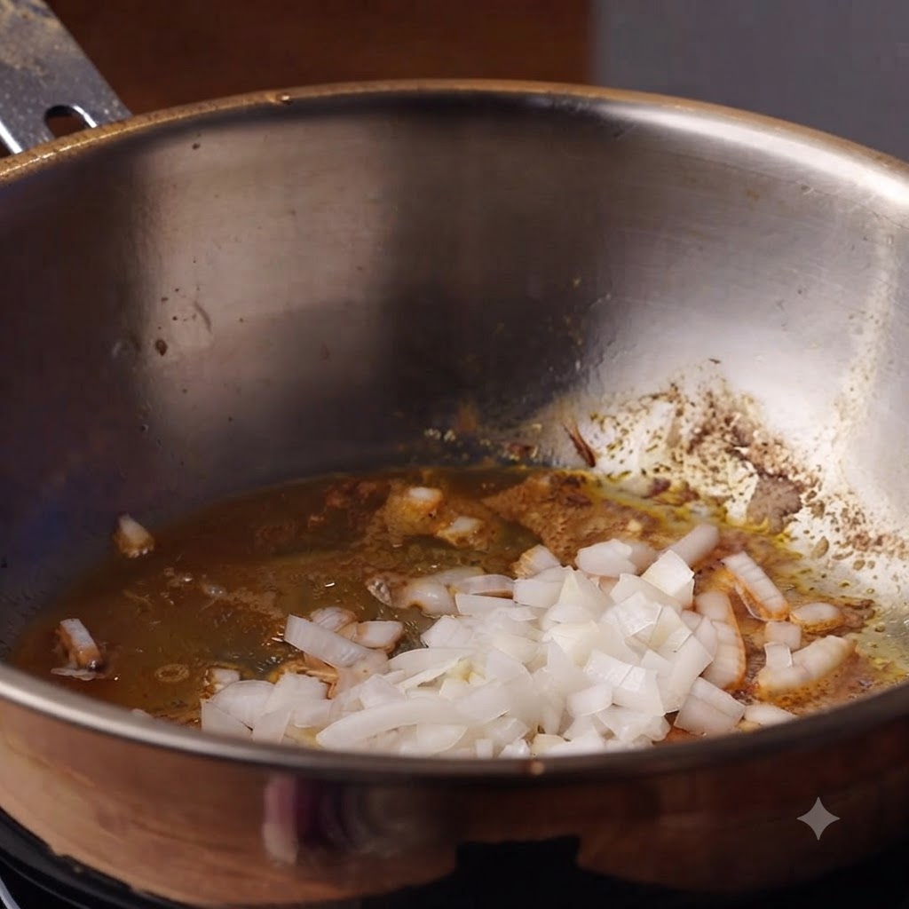 深鍋の油の中で炒められている玉ねぎとにんにく。