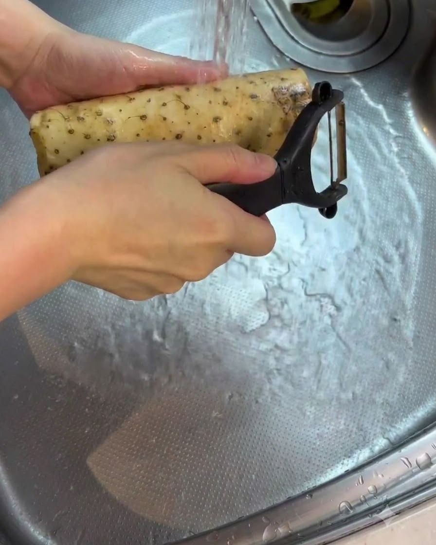 シンクの流水で皮をむいた山芋を洗っている様子。
