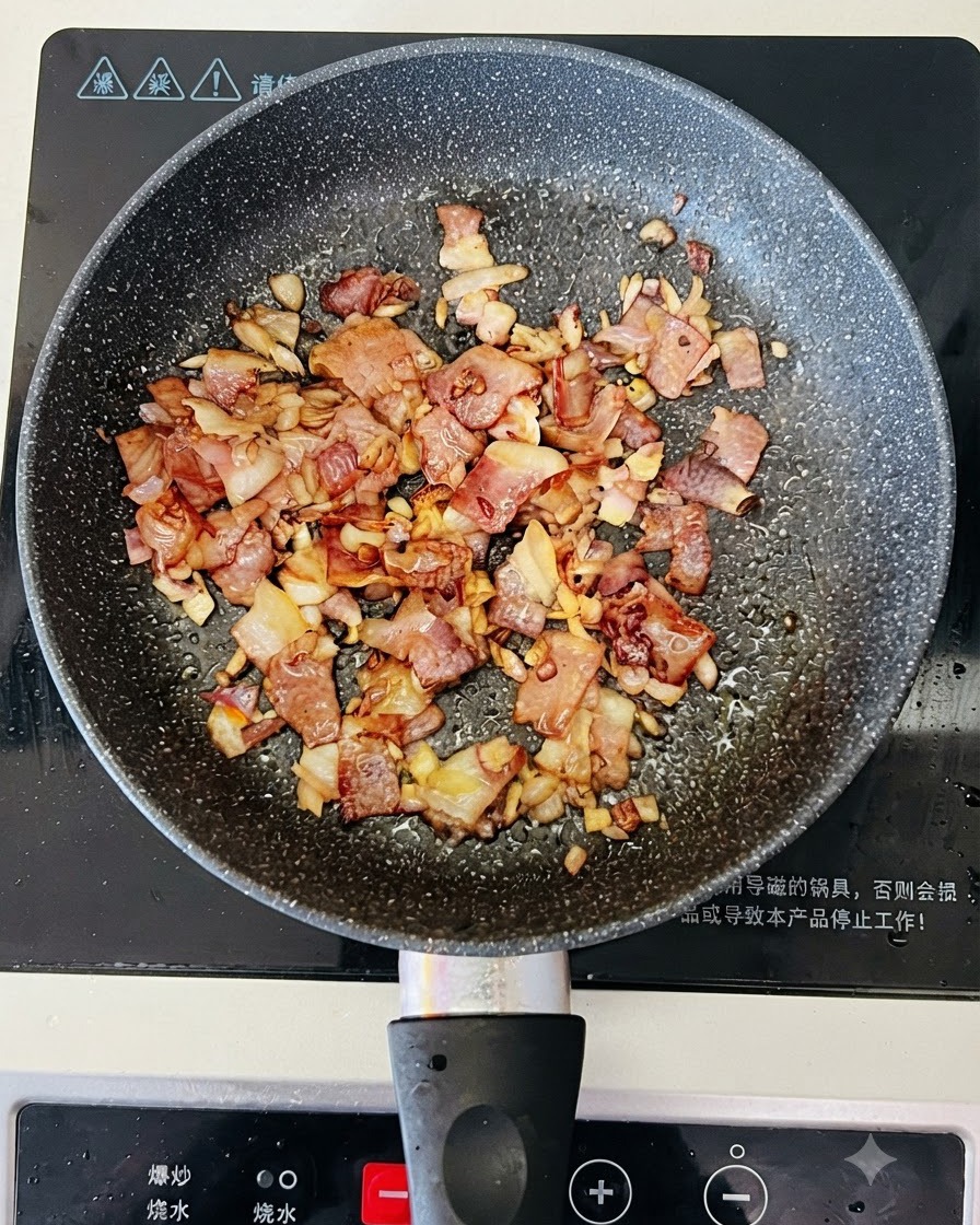 調理中のベーコンと玉ねぎが入ったフライパンに、ボウルから透明な水が注がれている様子。